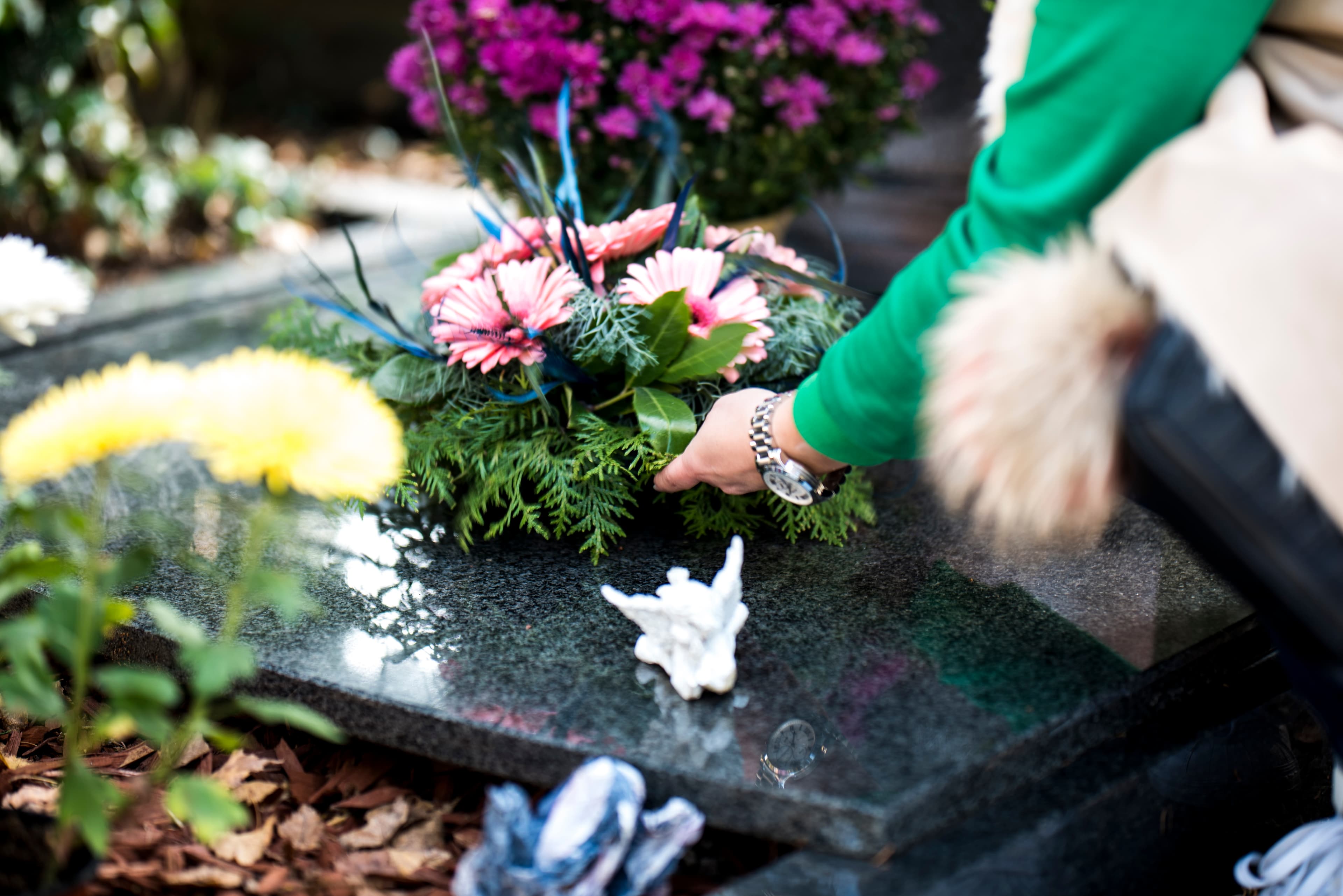 A memorial-care professional placing flowers at a gravesite